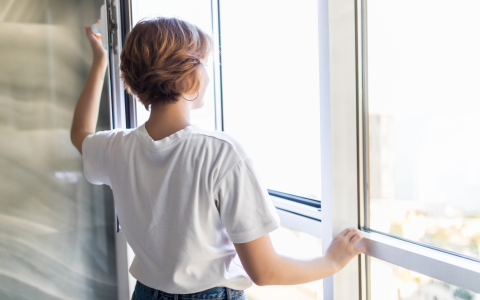 Frau öffnet Fenster zum Lüften