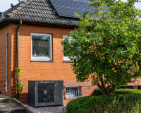 Wärmepumpe System E steht vor saniertem Haus