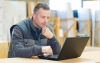 Installateur sitzt vor Laptop.