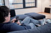 Mann liegt auf Sofa und bedient die Dimplex Home App